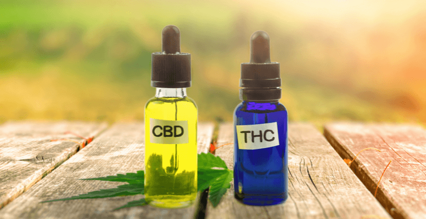 two-bottles-of-cbd-and-thc-oil-standing-on-wooden-table-with-a-hemp-leaf
