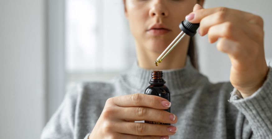 woman-dropping-CBD-oil-from-pipette-into-glass-bottle.jpg
