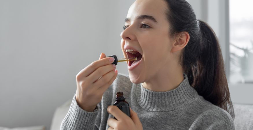 woman-dropping-CBD-from-glass-pipette-in-mouth.jpg