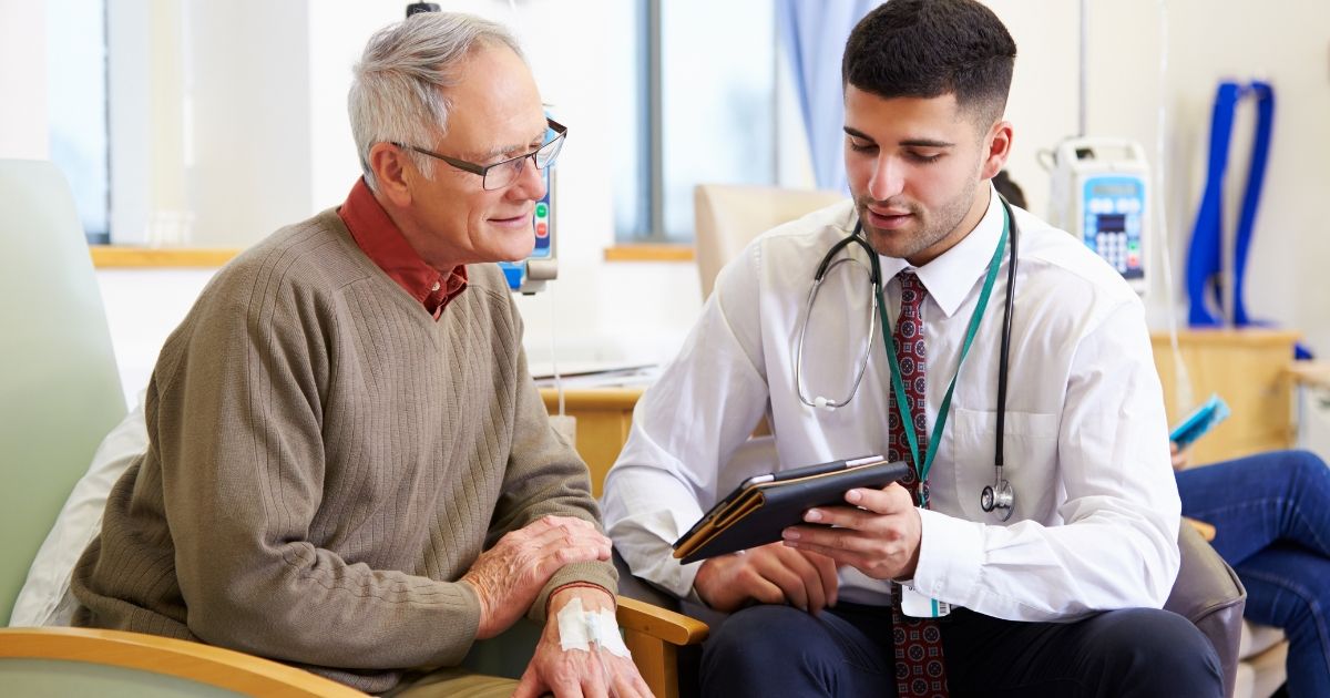 doctor showing elderly patient something on tablet