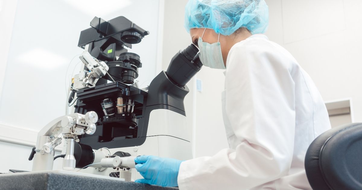 woman looking through a microscope in a labotory