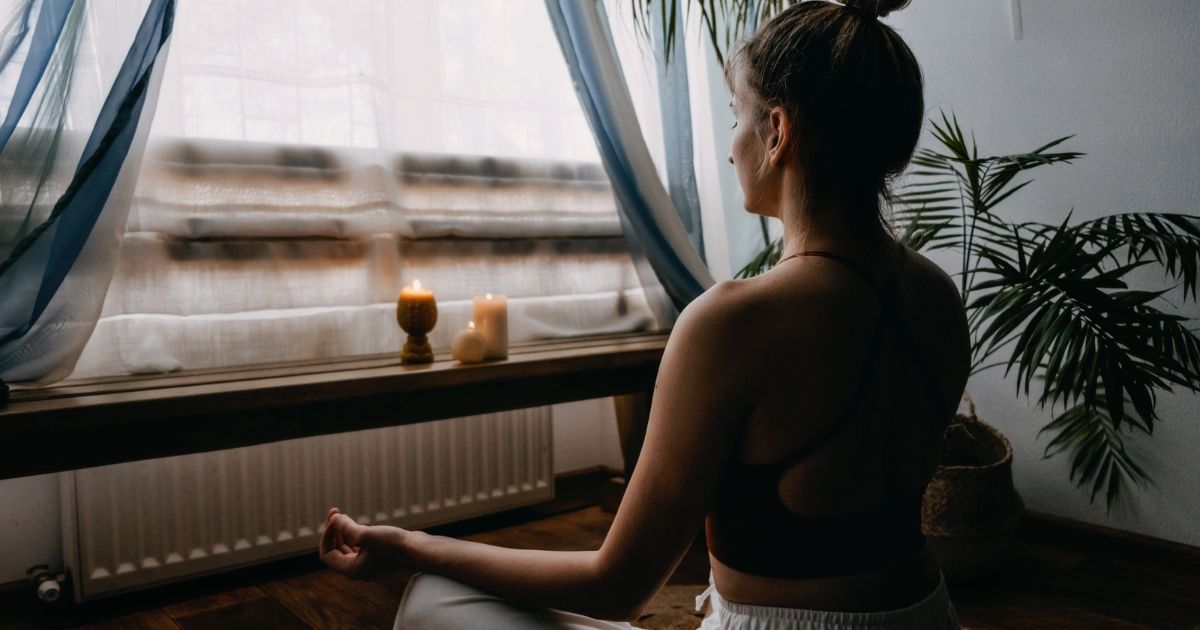woman sitting in front of window and meditating