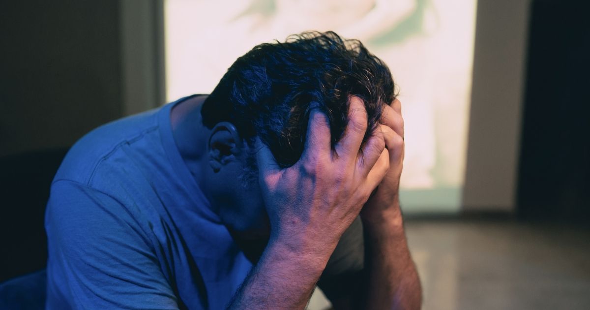 man holding his head looking stressed 