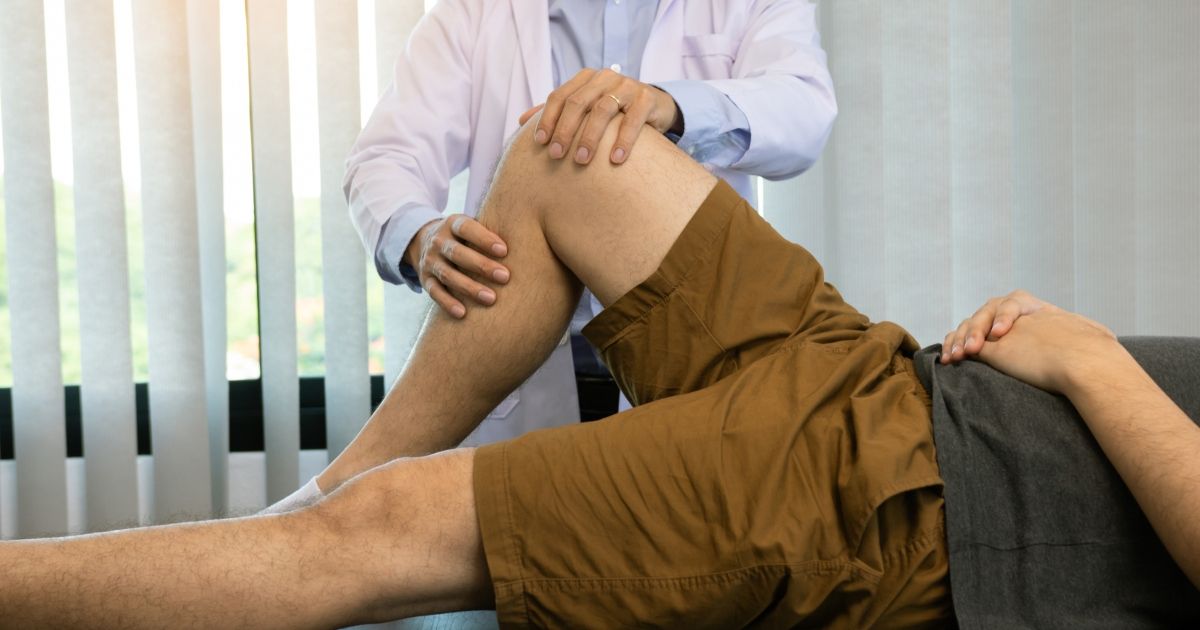 physical therapist performing knee exam on patient 