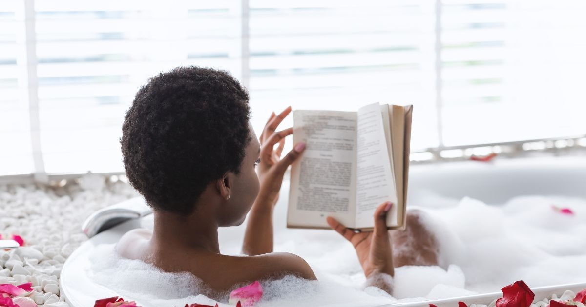 woman taking a bath while reading a book