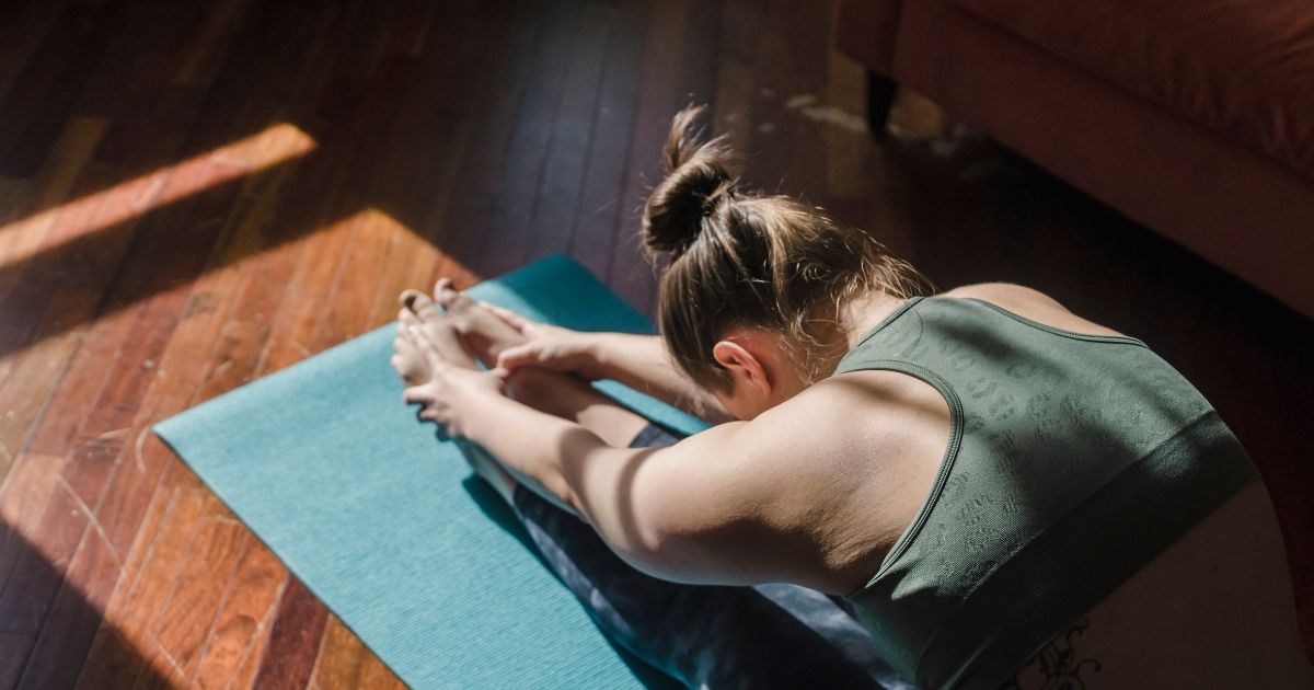 woman in green top doing yoga on blue yoga matt